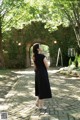 A woman in a black polka dot dress standing on a brick walkway.