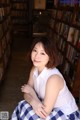 A woman sitting in front of a book shelf in a library.