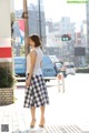 A woman in a white shirt and blue and white checkered skirt.