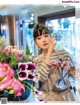 A woman holding a vase of flowers in front of a window.