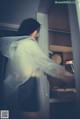 A woman in a white raincoat standing in a bathroom.