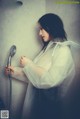 A woman in a white raincoat holding a shower head.