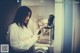 A woman standing in front of a mirror holding a hair dryer.