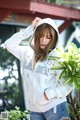 A woman in a white hoodie and denim shorts posing for a picture.