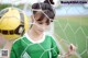 A young woman holding a soccer ball in front of a net.