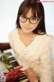 A woman wearing glasses sitting at a piano with a rose.