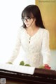 A woman in a white dress playing a piano.