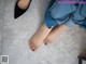 A woman's feet in black shoes on a tiled floor.