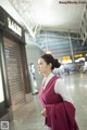 A woman in a pink and white dress walking through an airport.