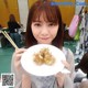 A woman holding a plate of food with chopsticks.