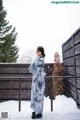 A woman in a blue kimono standing in the snow.