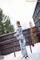 A woman in a blue and white kimono standing in the snow.