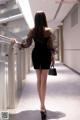 A woman in a black dress is walking down a hallway.