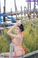 A woman in an orange bikini sitting on a wooden fence.