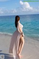 A woman in a long dress standing on a beach.