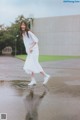 A woman in a white dress is walking in the rain.