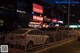 A row of parked cars on a city street at night.