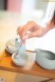 A woman is pouring tea into a small bowl.