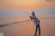 A woman standing on a beach at sunset.