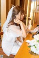 A woman in a wedding dress sitting at a table.