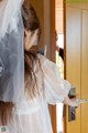 A woman in a wedding dress is opening a door.