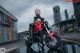 A woman sitting on a red motorcycle in the middle of a street.