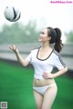 A woman in a white shirt and white panties playing with a soccer ball.