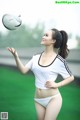 A woman in a white shirt and panties playing with a soccer ball.