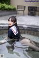 A woman in a sailor outfit is sitting in a pool.