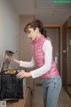 A woman in a pink vest is opening a black bag.