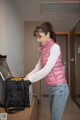 A woman in a pink vest is opening a black bag.