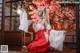 A woman in a red and white kimono sitting on the floor.