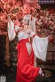 A woman in a red and white kimono holding a sword.