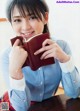 A woman sitting at a table holding a book.