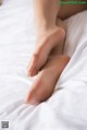 A close up of a woman's bare feet on a bed.