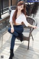 A woman sitting on a chair on a wooden deck.