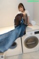 A woman sitting on top of a washing machine with her feet up.