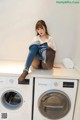 A woman sitting on top of a washing machine.