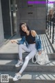 A woman sitting on the steps of a building wearing white pants and a denim jacket.