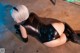 A woman in a black leather outfit laying on the ground.