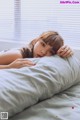 A woman laying on top of a bed next to a pillow.