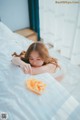 A woman laying on a bed eating a piece of fruit.