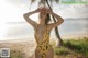 A woman in a yellow leopard print swimsuit standing on a beach.