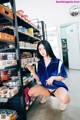 A woman crouching down in front of a shelf of food.