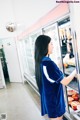 A woman standing in front of a refrigerator filled with food.