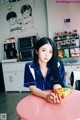 A woman sitting at a pink table holding a bag of chips.