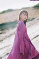 A woman in a purple dress standing on a beach.