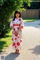 A young girl in a red and white kimono standing on a path.