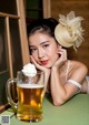 A woman sitting at a table with a glass of beer.