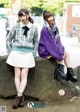 A couple of young women sitting on top of a rock.